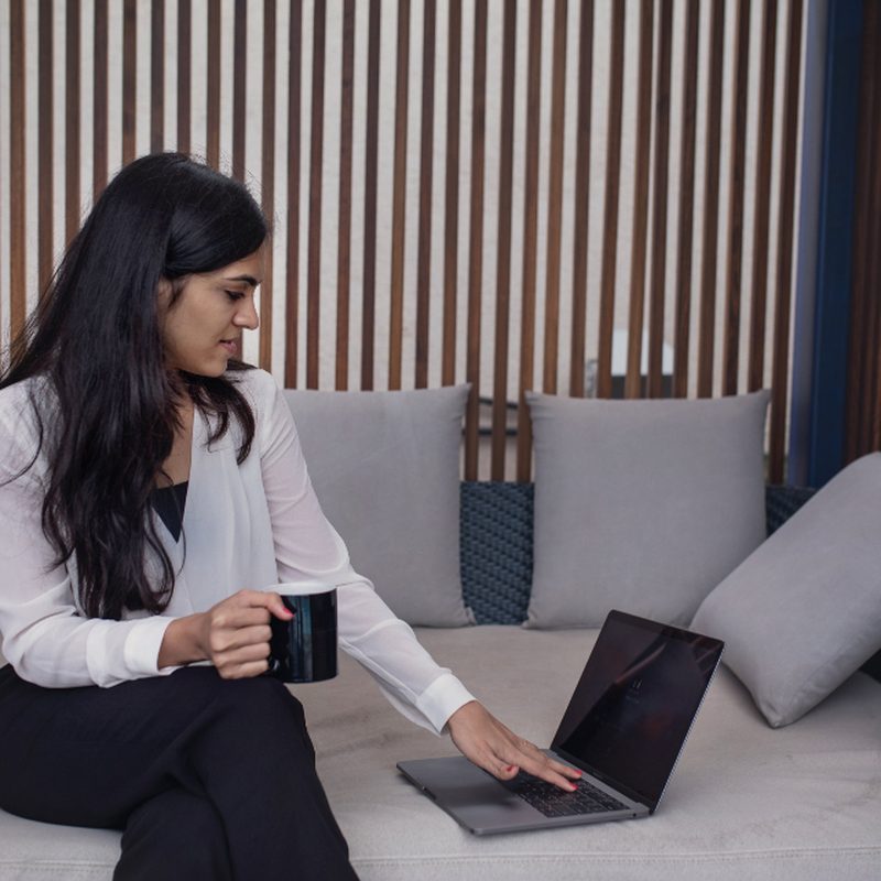 A woman sitting with a laptop and a mug of coffee
