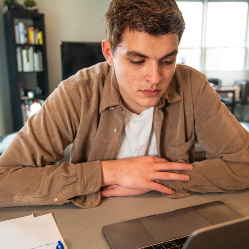 A young man working at a laptop in a bright room